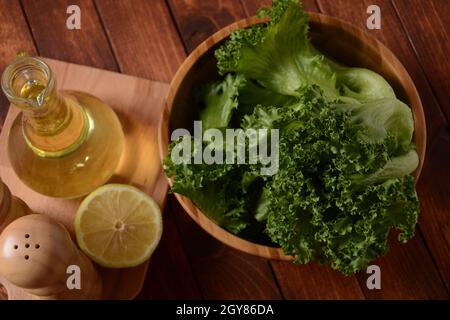 Grüne Batavia-Salatblätter auf Holzhintergrund. Bereit zum Kochen von Salat Stockfoto