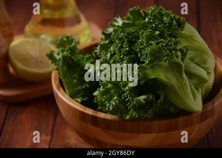 Grüne Batavia-Salatblätter auf Holzhintergrund. Bereit zum Kochen von Salat Stockfoto