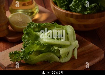 Grüne Batavia-Salatblätter auf Holzhintergrund. Bereit zum Kochen von Salat Stockfoto