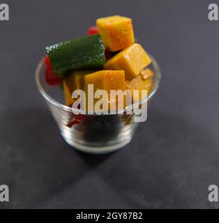 Glas mit farbenfroher mexikanischer Fruchtpaste auf schwarzer Oberfläche Stockfoto