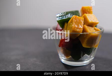 Glas mit farbenfroher mexikanischer Fruchtpaste auf schwarzer Oberfläche Stockfoto