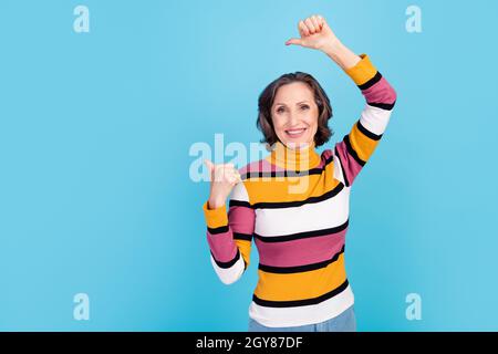 Foto von beeindruckt grauen Hairdo ältere Dame Index leeren Raum tragen gestreiften Pullover auf blauem Hintergrund isoliert Stockfoto