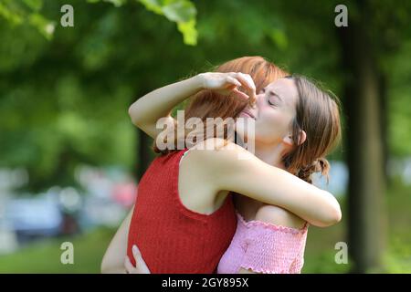 Frau umarmt ihre Freundin und hält ihre Nase, um schlechten Geruch in einem Park zu vermeiden Stockfoto