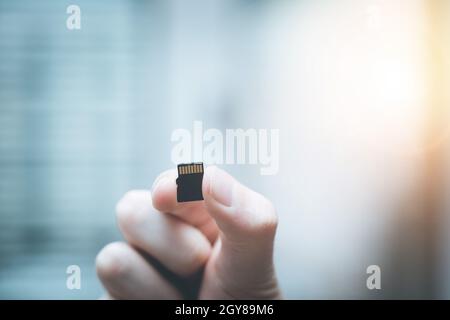 Der junge Mann hält eine kleine Speicherkarte in der Hand, Textraum Stockfoto