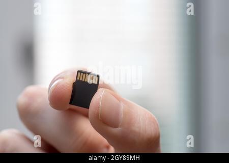 Der junge Mann hält eine kleine Speicherkarte in der Hand, Textraum Stockfoto