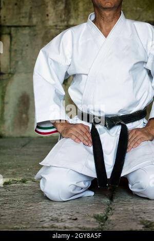 Schwarzer Gürtel Karate Mann sitzen auf EINER Position zu beginnen oder beenden Üben. Stockfoto