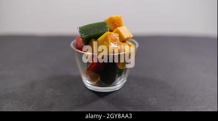 Glas mit farbenfroher mexikanischer Fruchtpaste auf schwarzer Oberfläche Stockfoto