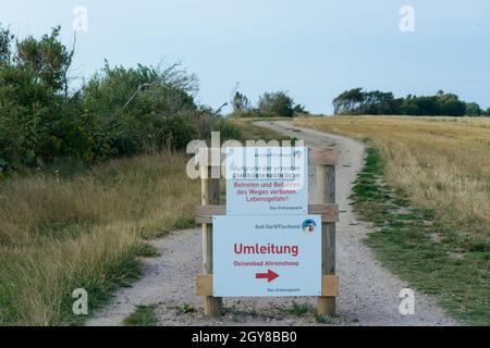 Weißes Warnschild mit Inschrift auf Deutsch - Vorsicht vor Klippen an der Ostsee auf dem Darss Stockfoto