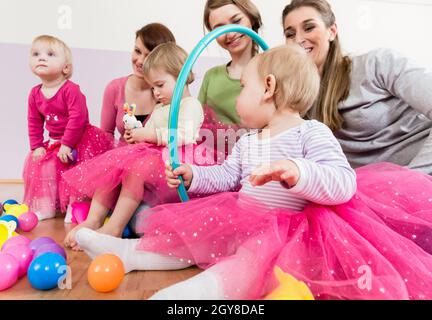 Kleinkind in rosa Kleid spielt mit Hula Hoop Reifen in der Spielgruppe Stockfoto