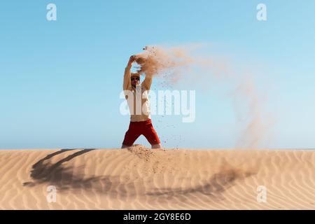 Ein einziger Mann wirft bei Sonnenaufgang Sand in die Namib-Wüste auf blauem Himmel. Reisekonzept Stockfoto