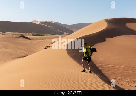 Fotograf, der in Deadvlei, Namib-Naukluft Nationalpark, Namibia, Afrika fotografiert. Getrockneter Boden mit Sand in der Namib Wüste bei Sonnenuntergang. Landschaftsfotografie Stockfoto