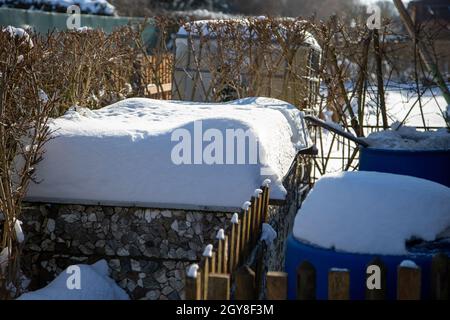 Im Winter ruht ein kleiner schneebedeckter Schottergarten Stockfoto