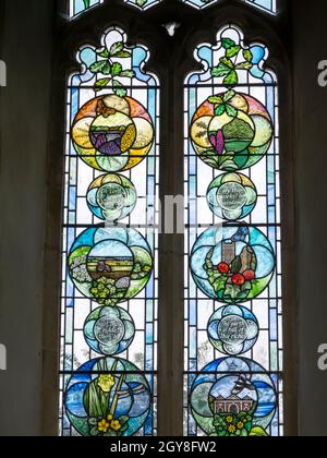 Ein Buntglasfenster, das die Jahreszeiten in der St. Mary's Church, Wortham, darstellt, eine sächsische runde Turmkirche in der Nähe von Redgrave, Suffolk, Großbritannien. Stockfoto