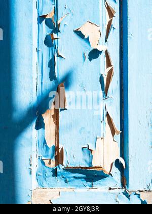 Teil einer alten hölzernen Außentür mit blätternder blauer Farbe an sonnigen Tagen Stockfoto