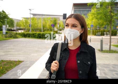 Porträt einer jungen Frau mit FFP2 KN95-Schutzmaske, die in der Stadtstraße läuft Stockfoto