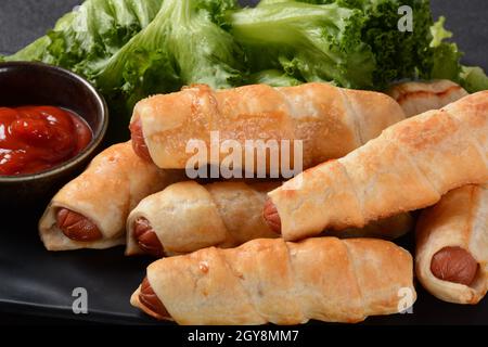 Wurstbrötchen. Weich gebackenes Brötchen (Teig) gefüllt mit Schweinewurst für Fast-Food-Frühstück oder Kaffeepause. Wurstrolle (Hot Dog). Stockfoto