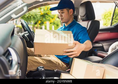Asiatische junge Lieferung Mann Kurier in Uniform halten Dokumente Zwischenablage Checklisten Paketpostboxen in einem Auto für Service-Versand an den Kunden, auf Stockfoto