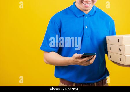 Aufgeregt Lieferservice Mann lächelnd trägt blaue Uniform halten Papierbehälter für Mitnehmen Pizzakartons Paket und zeigen Smartphone leeren Bildschirm, Stud Stockfoto