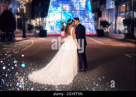 Paar auf ihre Hochzeitskleidung gegen weihnachten Straßendekoration in der Nacht Stockfoto