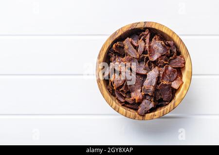 Rinderhackfleisch in Scheiben. Getrocknetes Rindfleisch in einer Schüssel auf einem weißen Tisch. Draufsicht. Stockfoto