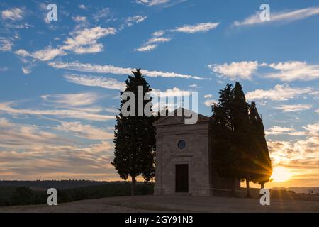 Atemberaubender Sonnenaufgang in der Alten Kirche von Vitaleta mit Bäumen auf beiden Seiten in San Quirico d'Orcia, in der Nähe von Pienza, Toskana, Italien im September Stockfoto