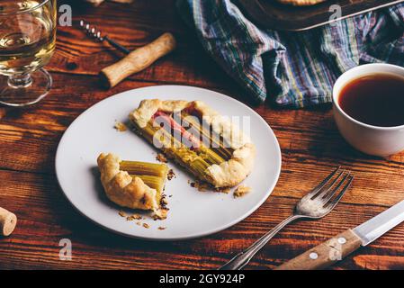 Rhabarber Mini-Galette auf weißem Teller mit einem Glas Wein und einer Tasse Kaffee Stockfoto