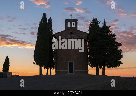 Atemberaubender Sonnenuntergang in der alten Kirche von Vitaleta mit Bäumen auf beiden Seiten in San Quirico d'Orcia, in der Nähe von Pienza, Toskana, Italien im September Stockfoto