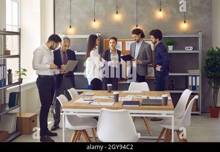 Lächelnde Kollegen, die zusammen in einem informellen Gespräch im Büro des Unternehmens zusammenarbeiten Stockfoto