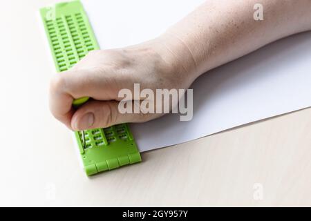 Schreiben von Wörtern in Braille-Schrift mit Schiefer und Eingabestift aus der Nähe Stockfoto