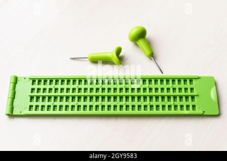 Plastik Braille Schreibschiefer und Stylus auf braunem Tisch Stockfoto