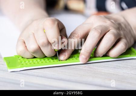 Vorderansicht des Drucks in Brailleschrift mit Schiefer und Eingabestift aus der Nähe Stockfoto