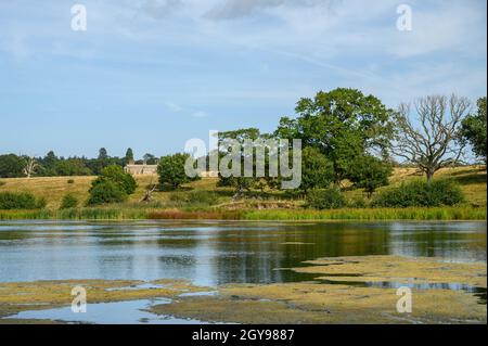 Blick auf die Felbrigg Hall in der Ferne über einen Teich, Bäume und Felder, Norfolk, England, fotografiert von einem öffentlichen Fußweg. Stockfoto