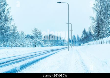 Leere Straße in der Stadt an einem kalten Wintertag mit Schnee. Lichtmasten an den Straßenrändern. Stockfoto