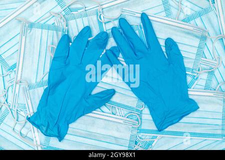 Ein Paar dünne blaue medizinische Latexhandschuhe und eine Menge medizinische Gesichtsmaske. Medizinische Einweghandschuhe aus Gummi und Maske. Schutzsubjekte. Stockfoto