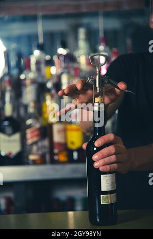 Der Kellner öffnete eine Flasche Wein mit einem Weinöffner an der Theke, unten in der Bar Stockfoto