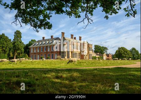 Blick auf die Felbrigg Hall über Grasfelder mit weidenden Schafen, Norfolk, England, fotografiert von einem öffentlichen Fußweg. Stockfoto