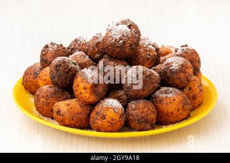 Kleine Kugeln aus frisch gebackenen hausgemachten Hüttenkäse-Donuts auf einem Teller auf einem hölzernen Hintergrund. Stockfoto