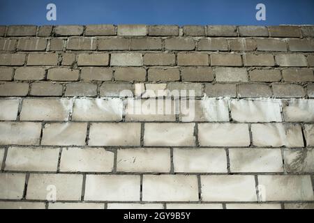 Wand aus Betonblöcken. Die Wand des Gebäudes auf der Baustelle. Nicht ausgekleidete Oberfläche des Hauses. Zementierte Nähte aus Mauerwerk. Stockfoto