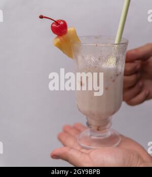 Männliche Hände halten leckeren Vanille-Milchshake mit grauem Hintergrund Stockfoto