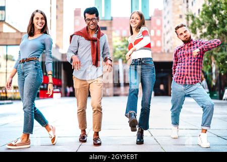 Multikulturelle Freunde, die im Stadtzentrum spazierengehen und lustige verrückte Moves spielen - fröhliche Jungs und Mädchen, die sich auf Party-Stimmung durch urbane Straßen amüsieren Stockfoto