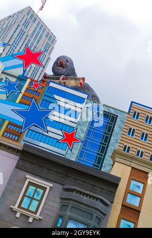 Kartoonische Gebäude mit dem aufragenden König Kong im Hintergrund mit rot-weißen und blauen Sternen, die auf den Gebäudefassaden überlagert sind Stockfoto