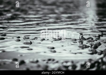 Plastikflasche liegt auf dem steinigen Strand, Umweltverschmutzung Stockfoto