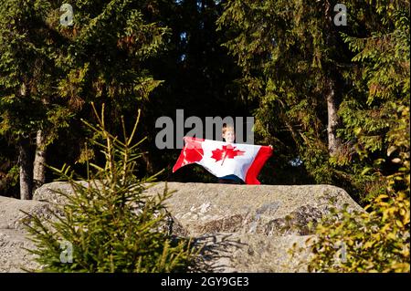 Alles Gute Zum Kanada Tag. Junge mit großer kanadischer Flagge Feier in den Bergen. Stockfoto
