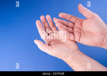 Die Handflächen von zwei männlichen Händen mit blauem Hintergrund Stockfoto