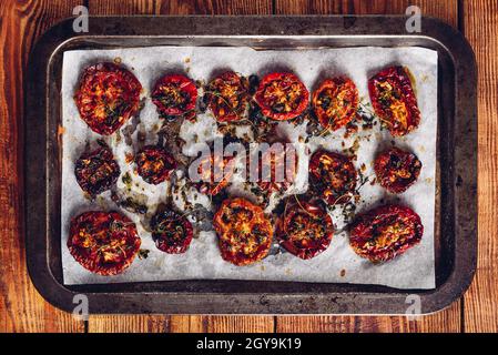 Backblech voller frisch gekochter sonnengetrockneter Tomaten mit Thymian und Olivenöl bereit zum Einkochen. Blick von oben. Stockfoto