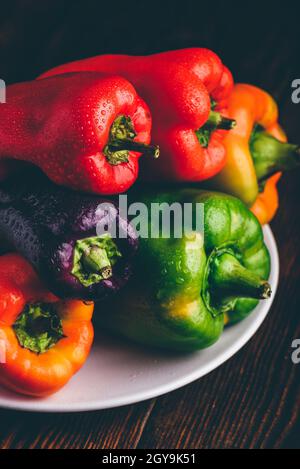 Bunte, frische Paprika auf dem Teller auf Holzboden Stockfoto