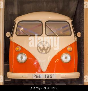 Vorderansicht eines orangefarbenen und weißen VW Kombi/Bus/Transporter, der in einer Garage in Valetta Malta geparkt ist. Keine Personen. Stockfoto