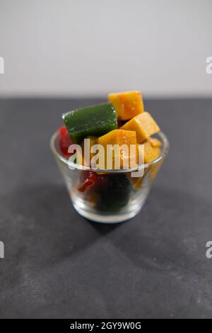 Glas mit farbenfroher mexikanischer Fruchtpaste auf schwarzer Oberfläche Stockfoto