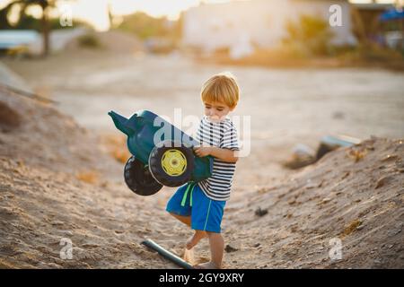 Kleiner Junge, der in der Wüste mit Spielzeugautos spielt Stockfoto