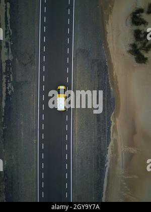 Gelber Wohnmobil auf leerer Straße am Sandstrand in Holland, Europa Stockfoto